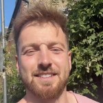 Sam Thompson smiling at the camera in a video message filmed outdoors in the sunshine