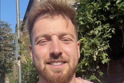 Sam Thompson smiling at the camera in a video message filmed outdoors in the sunshine