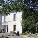 The white Georgian-style Scolton Manor House near Haverfordwest, with cafe tables under trees in front