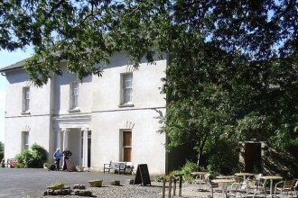 The white Georgian-style Scolton Manor House near Haverfordwest, with cafe tables under trees in front