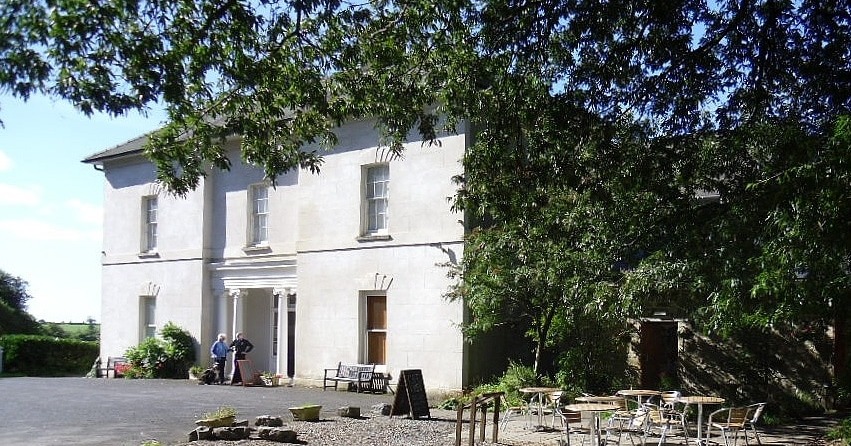 The white Georgian-style Scolton Manor House near Haverfordwest, with cafe tables under trees in front