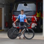 Siôn Jones in Ride Revolution Coaching race kit holding his time trial bike in front of a fire engine at Tumble Fire Station