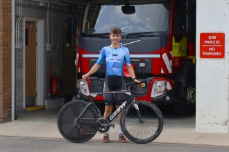 Siôn Jones in Ride Revolution Coaching race kit holding his time trial bike in front of a fire engine at Tumble Fire Station
