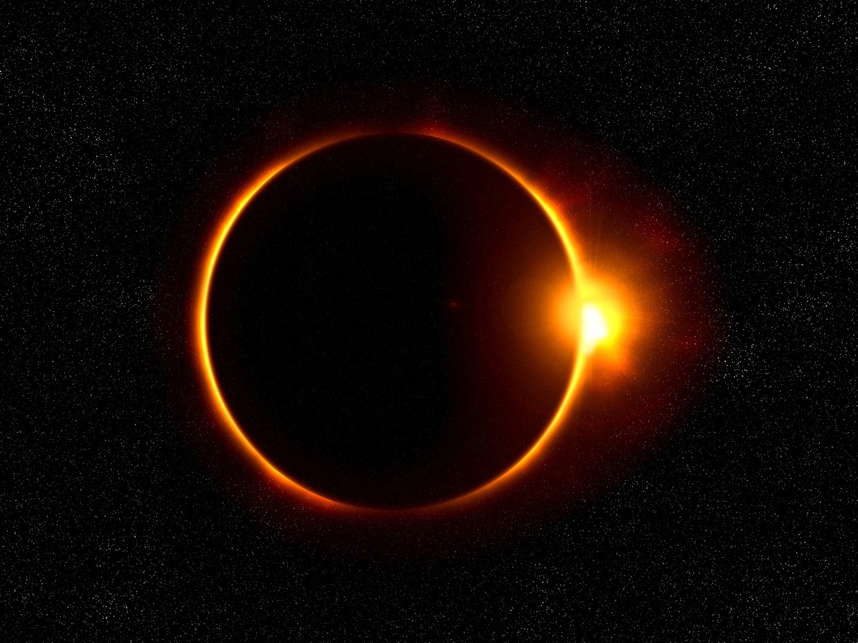 A solar eclipse showing the dark disc of the moon ringed by orange light against a starry sky, with a bright flare at its right edge