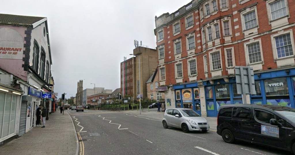A Street View image of St Helen’s Road in Swansea, with the YMCA building on the right and shops lining the street