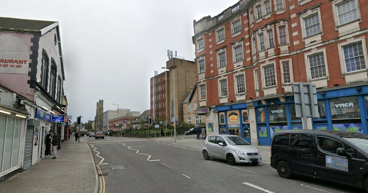 A Street View image of St Helen's Road in Swansea, with the YMCA building on the right and shops lining the street