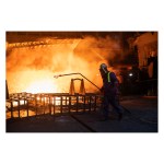 A steelworker in a heat mask and visor silhouetted against molten metal at Port Talbot steelworks