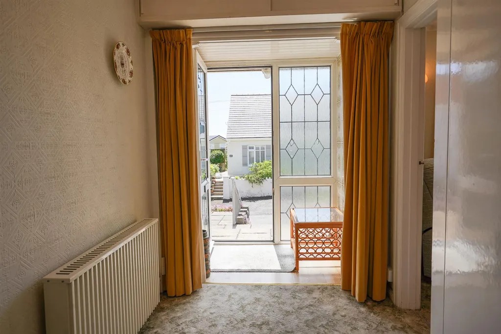 A hallway looking out through the open front door to the street beyond