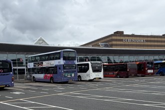 Buses lined up at Swansea bus station with the former Debenhams building behind