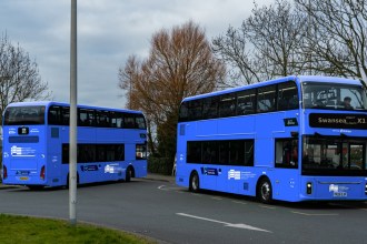 Two double-decker buses in blue South West Wales Network livery with Swansea on the destination board, a Swansea Bay News mock-up