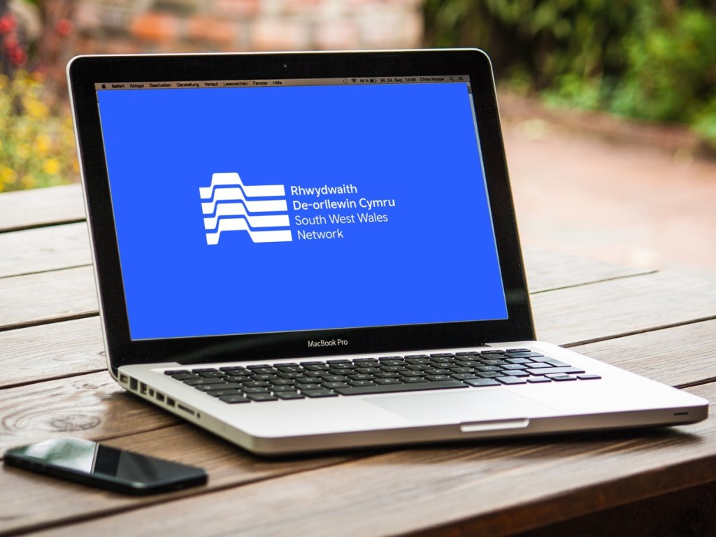 The South West Wales Network brand on a laptop screen, a Swansea Bay News composite