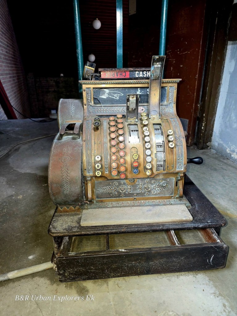 An ornate vintage brass cash register on a wooden surface inside the derelict cinema
