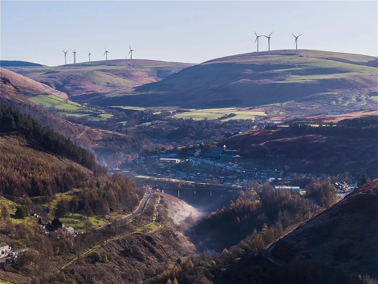 The Upper Afan Valley with a village and viaduct in the valley floor, wind turbines on the hilltops above