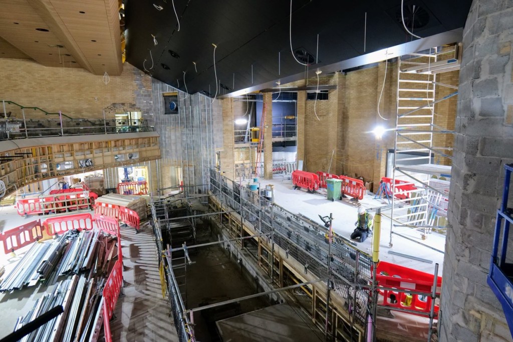 View from the Yr Aelwyd balcony down towards the stage end, with the black ceiling above and scaffolding below