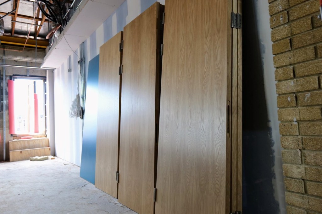 New oak doors stacked against a wall inside Yr Aelwyd ready to be hung