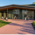 Architect's concept render of the Ysgol Calon Lân entrance, with glazed doors etched with tree designs, a timber canopy and children and families outside