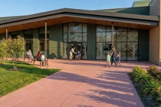Architect's concept render of the Ysgol Calon Lân entrance, with glazed doors etched with tree designs, a timber canopy and children and families outside