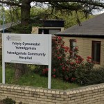 The entrance sign and low brick buildings of Ystradgynlais Community Hospital, with the bilingual Ysbyty Cymunedol Ystradgynlais sign in front