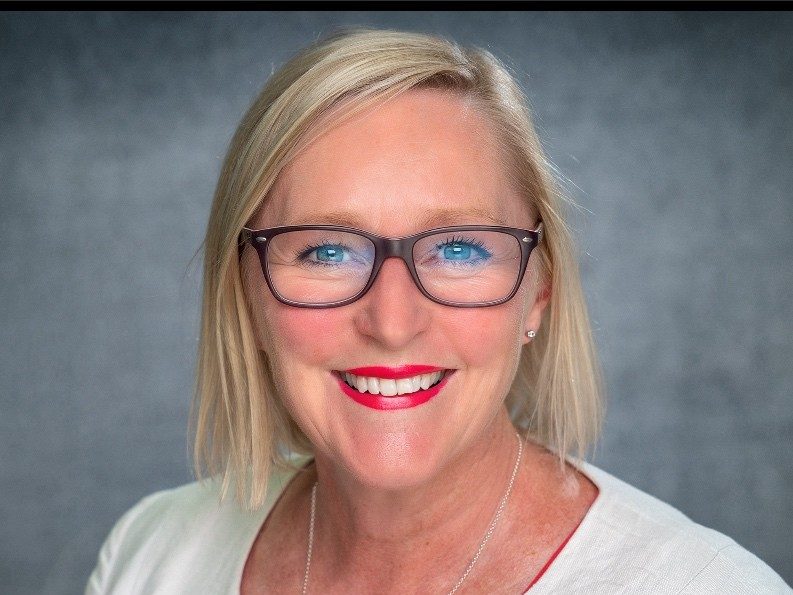 A portrait image of Abigail Harris, Swansea Bay University Health Board's Chief Executive. A blonde-haired woman with galsses wearing a white top.