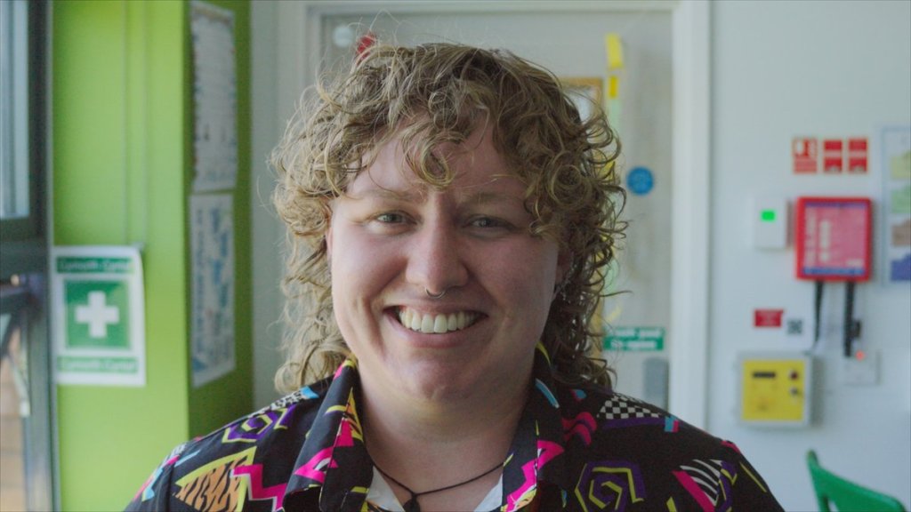 Alex Williams, science teacher at Ysgol Gymraeg Ystalyfera Bro Dur, smiling in a science classroom in the S4C series Athrawon