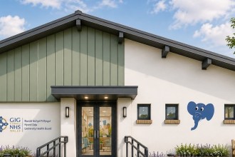 Artist's impression of a single-storey children's centre with white and sage green walls, a blue elephant painted beside the windows and Hywel Dda NHS signage at the entrance