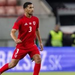 Ben Cabango in a red Wales shirt with the number 3, running during an away international