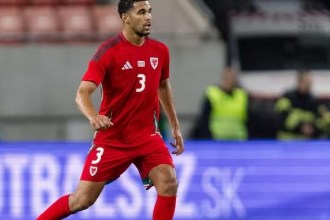 Ben Cabango in a red Wales shirt with the number 3, running during an away international