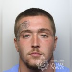 Dyfed-Powys Police custody photograph of Cameron Davies, a man with short cropped hair, a moustache and a tattoo on his forehead