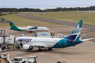 A WestJet Boeing 737-8 parked on the apron at Cardiff Airport with an Aer Lingus Regional ATR turboprop behind