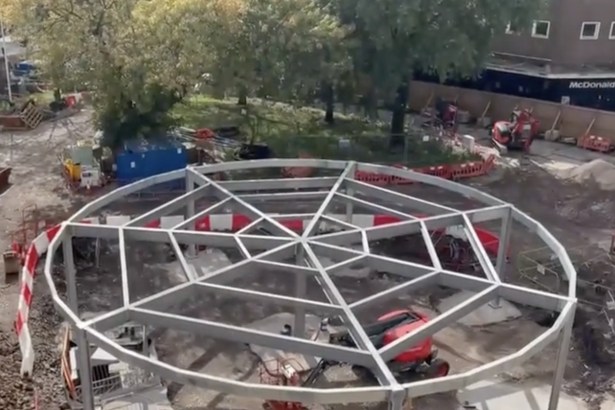 Circular steel frame of a pavilion under construction on the Castle Square Gardens site, with diggers and trees behind