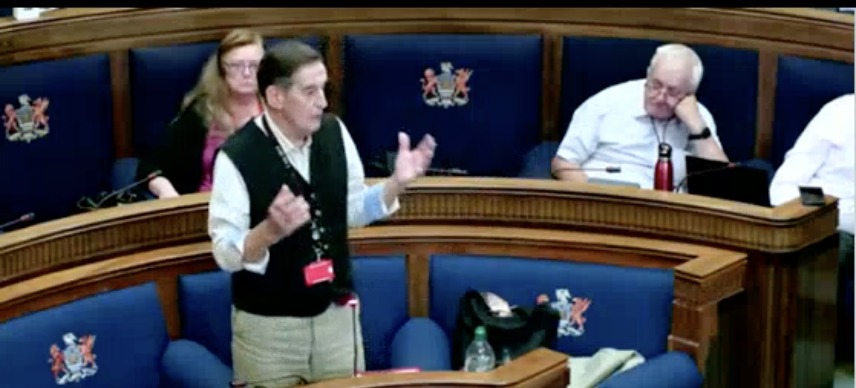 Cllr David Phillips standing and gesturing as he addresses the Swansea Council chamber