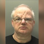 Custody image of Craig Henton, a bald man with glasses, against a grey background