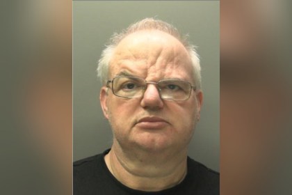 Custody image of Craig Henton, a bald man with glasses, against a grey background