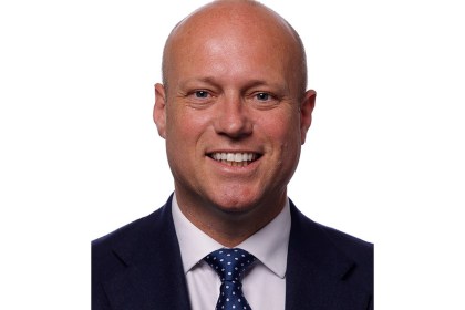 Official Senedd portrait of Dan Thomas MS, smiling in a navy suit and polka dot tie against a white background