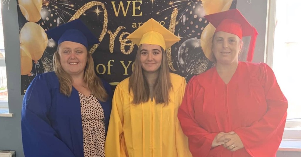 Three Inspiring Futures learners in caps and gowns standing together at a Community Cwtch graduation celebration