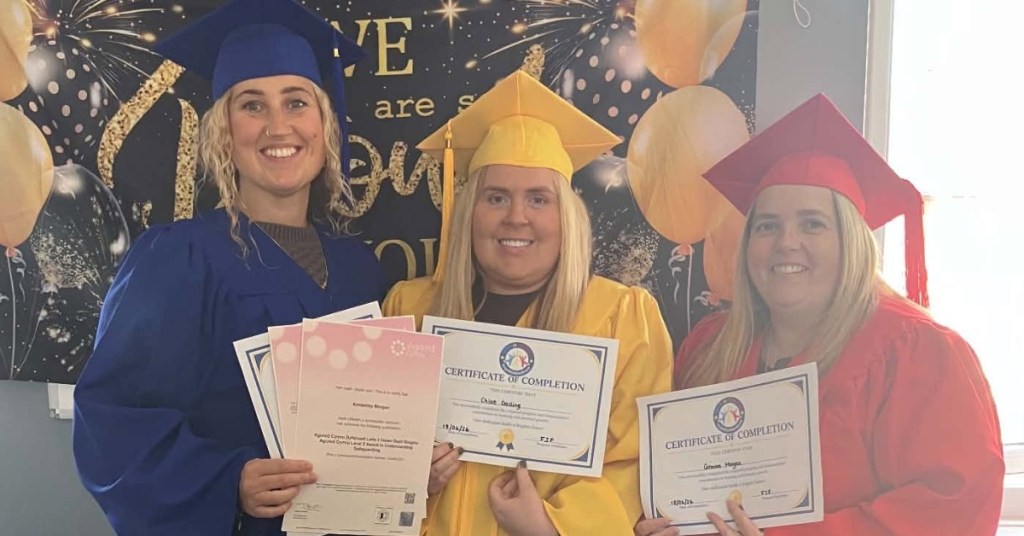 Three Inspiring Futures learners in blue, yellow and red caps and gowns holding up their certificates of completion