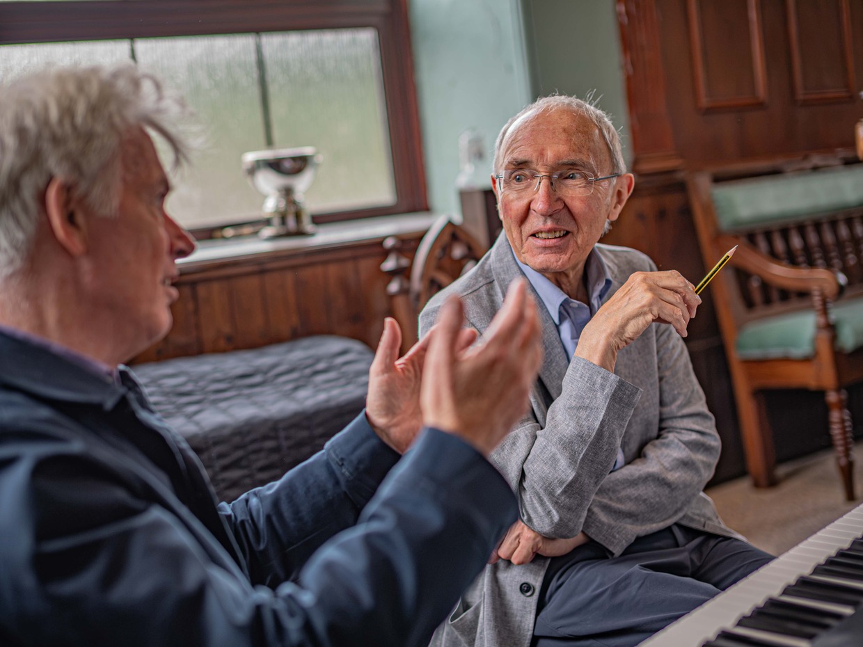 Librettist Patrick Young and composer Gareth Glyn in conversation at a piano during rehearsals for Fflamau Penyberth