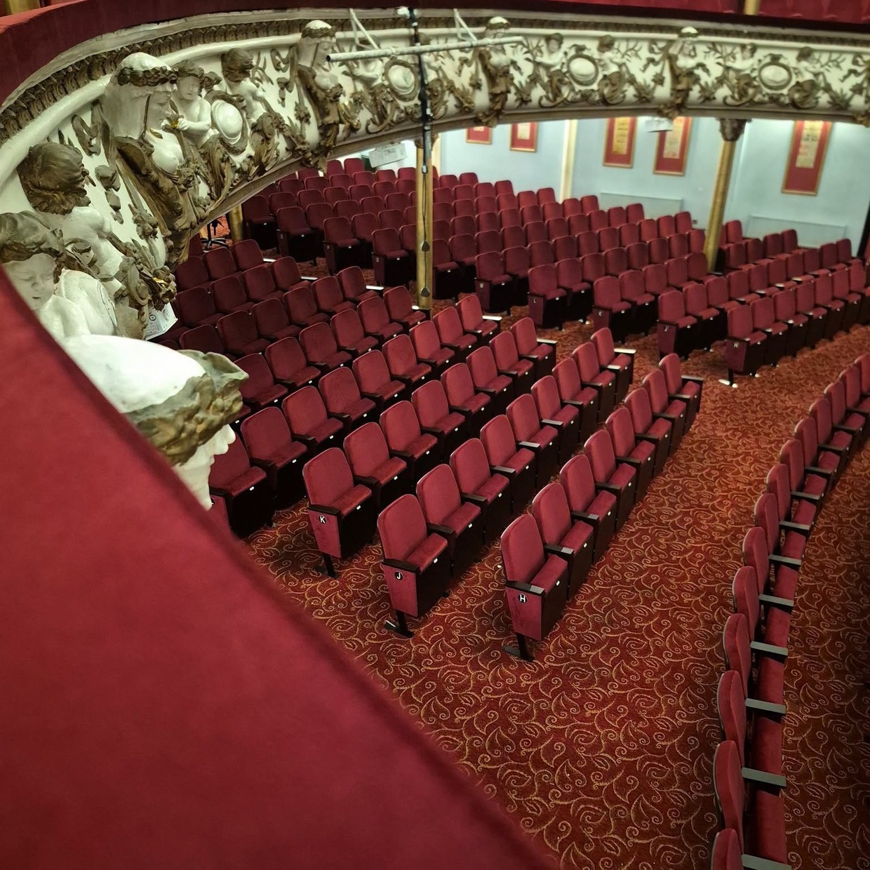 New red seats in curved rows at Swansea Grand Theatre beneath the ornate white and gold plasterwork of the circle fronts