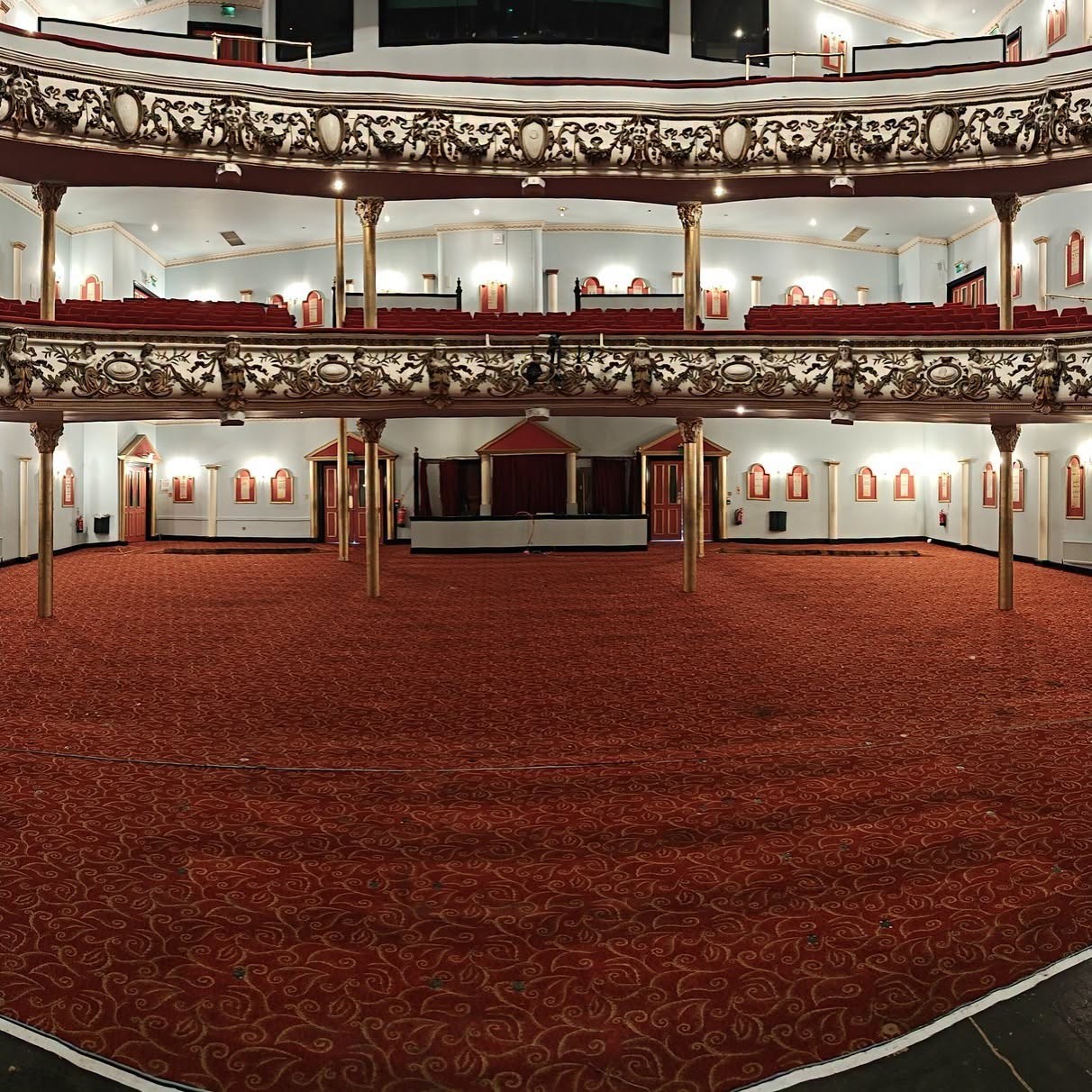 Swansea Grand Theatre's stalls stripped completely bare, showing an empty carpeted floor beneath the tiered balconies