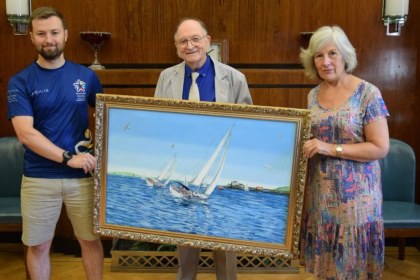 Jeff Phillips holds his oil painting of the Lord Mayor's Regatta at Swansea Guildhall with Cllr Cheryl Philpott and Lewis Bradley