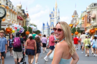 Joely McNamara smiling over her shoulder in a halter-neck dress on Main Street at a Florida theme park