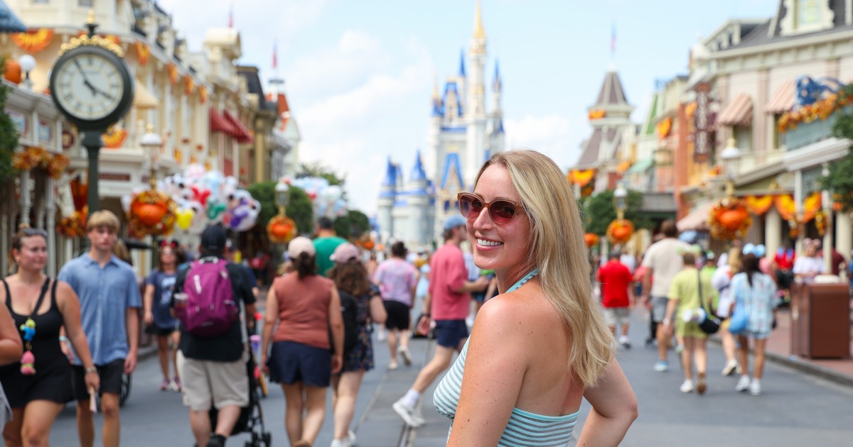 Joely McNamara smiling over her shoulder in a halter-neck dress on Main Street at a Florida theme park