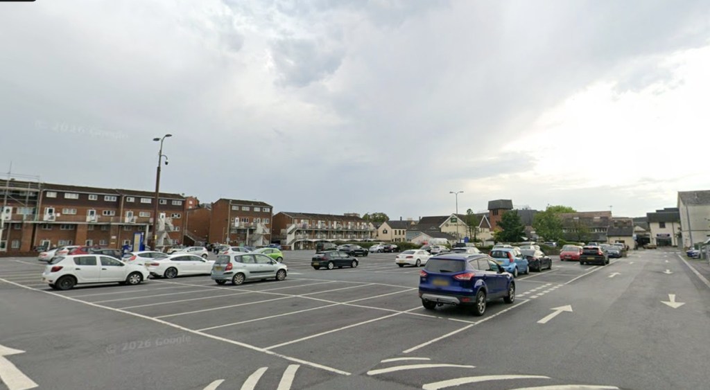 A wide view of John Street car park in Carmarthen with marked bays, parked cars and flats along the far side