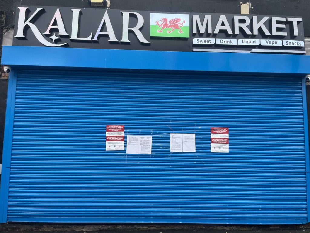 Kalar Market on Mansel Street with its blue shutter down and bilingual court closure notices taped to it