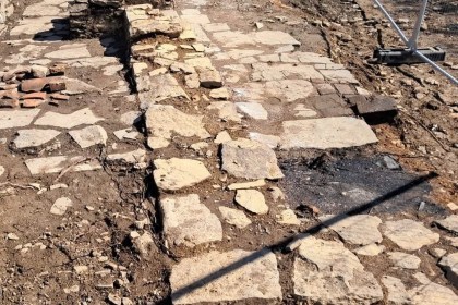 The excavated remains of a stone building on Kilvey Hill's summit, showing a flagged stone floor and low wall stub behind temporary fencing