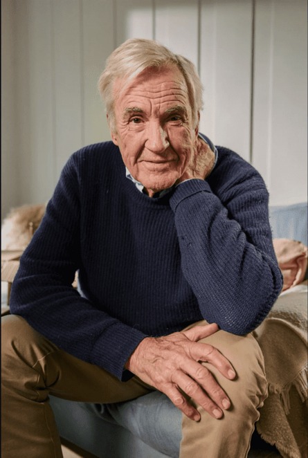 Actor Larry Lamb in a navy jumper sitting with his chin resting on his hand