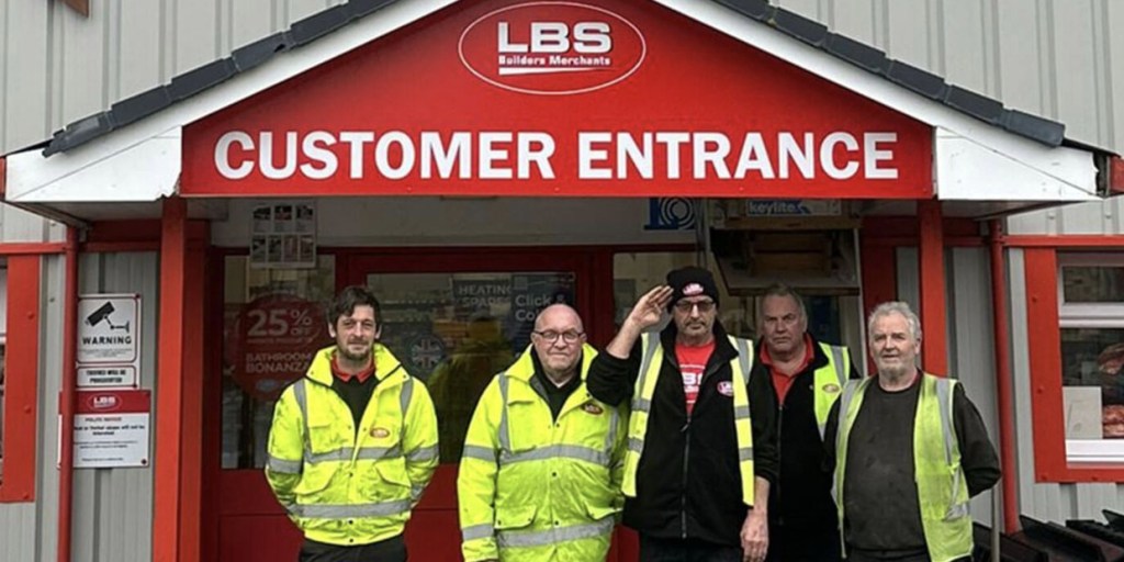 Five LBS staff in hi-vis jackets standing under the red Customer Entrance canopy of the Llandeilo branch