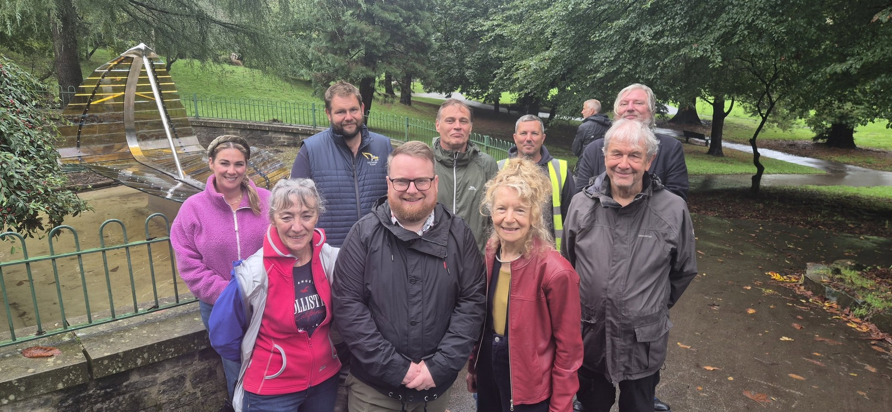 A group of people gathered beside the Leaf Boat sculpture at Cwmdonkin Park for its unveiling