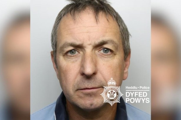 Custody image of Michael Fox, a middle-aged man with grey hair in a light blue polo shirt, with the Dyfed-Powys Police watermark