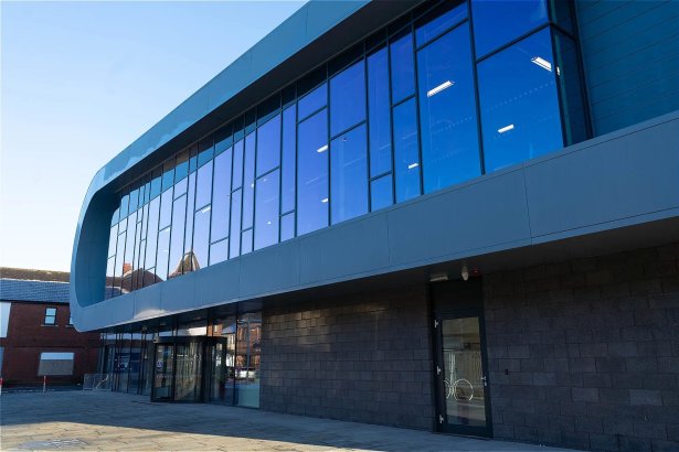 The new leisure centre in Neath town centre, with dark curved cladding wrapping a fully glazed upper storey